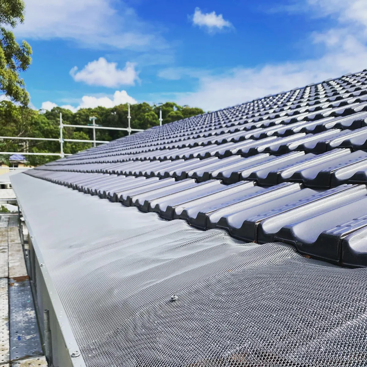 A finished tiled roof with mesh gutter guard along its edge