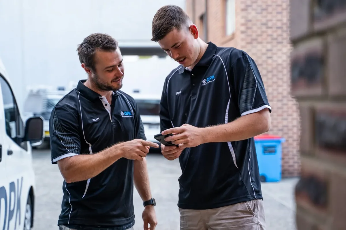 Two DPK team members checking a phone together on site