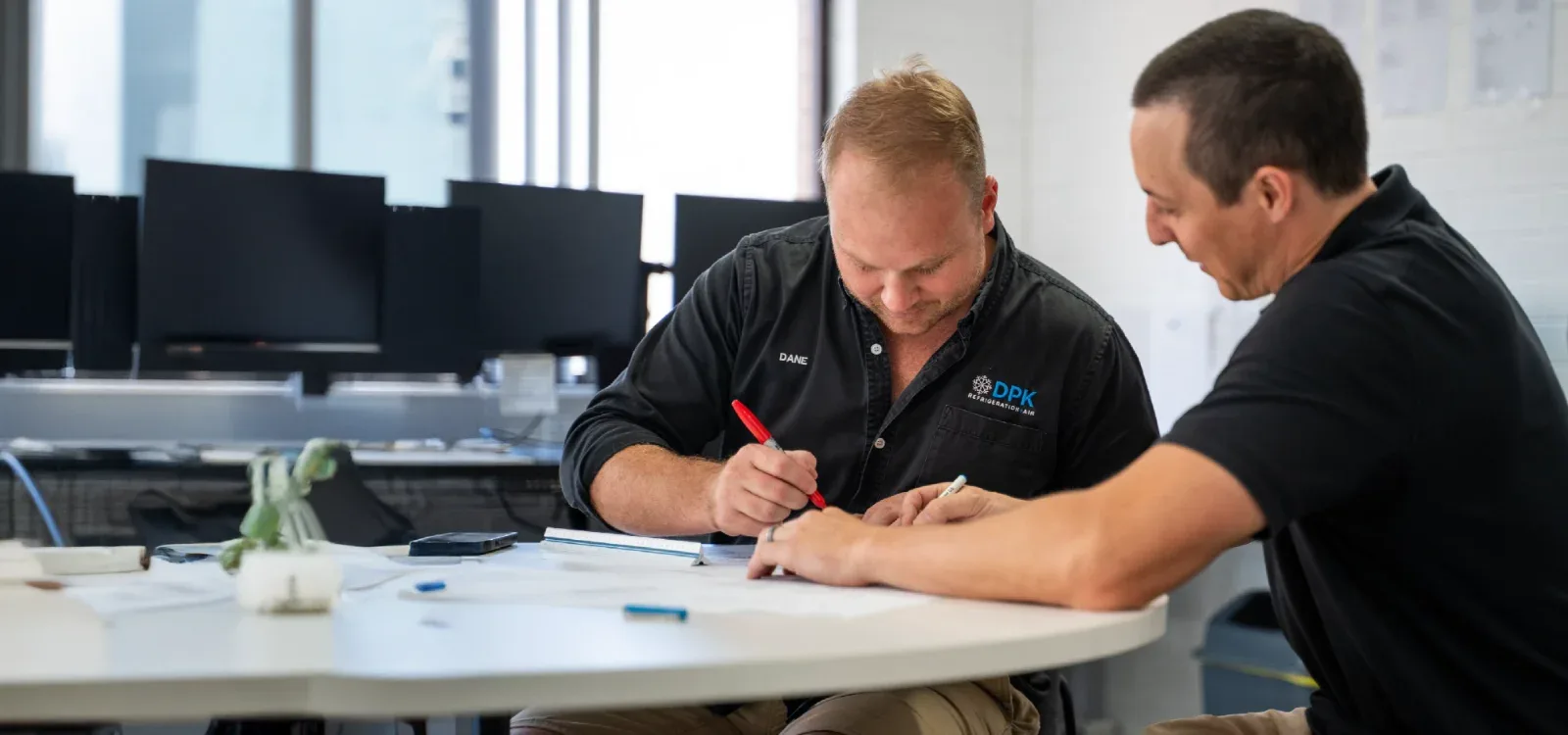 Dane and a DPK technician reviewing paperwork at the office