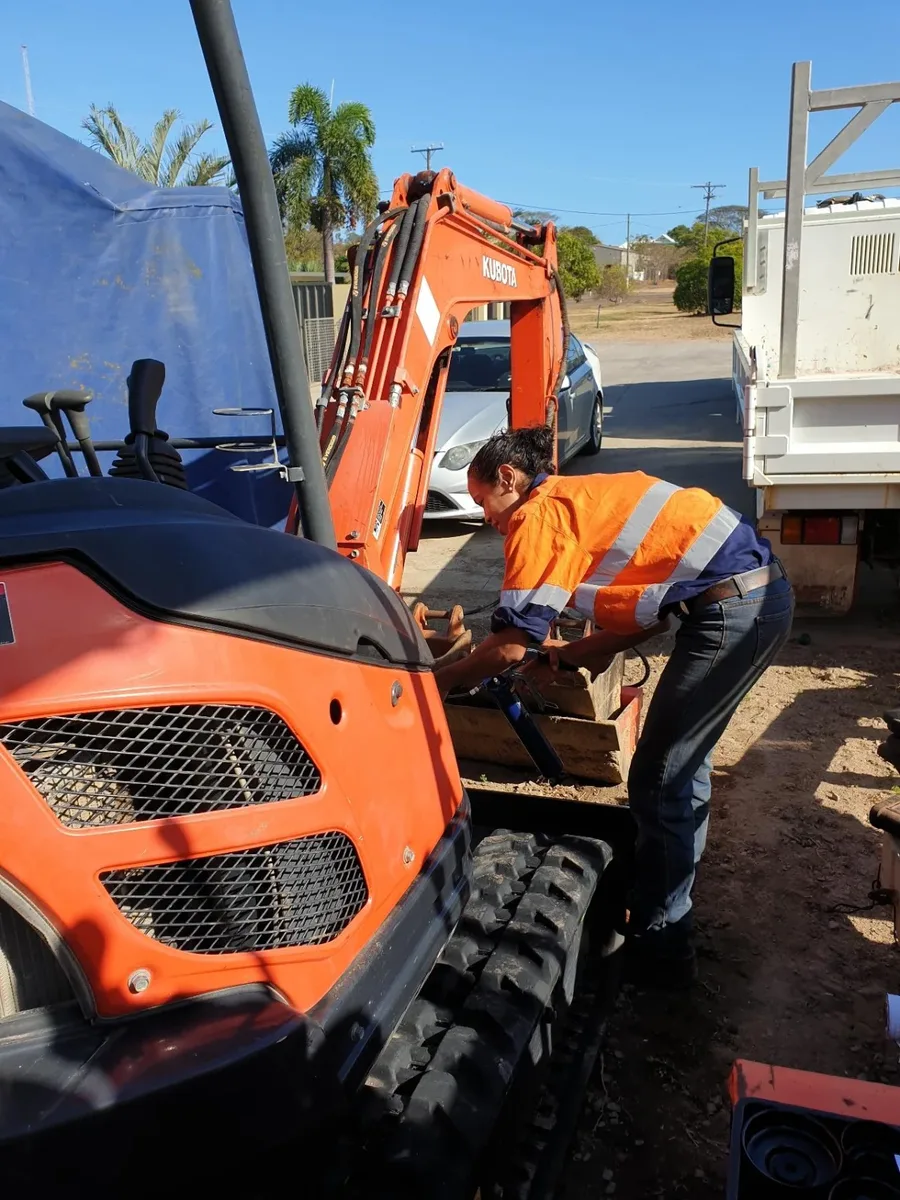 A worker in hi-vis at an orange excavator