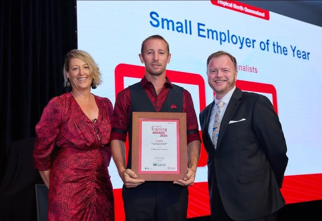 Three people on stage with a Training Awards plaque, Small Employer of the Year