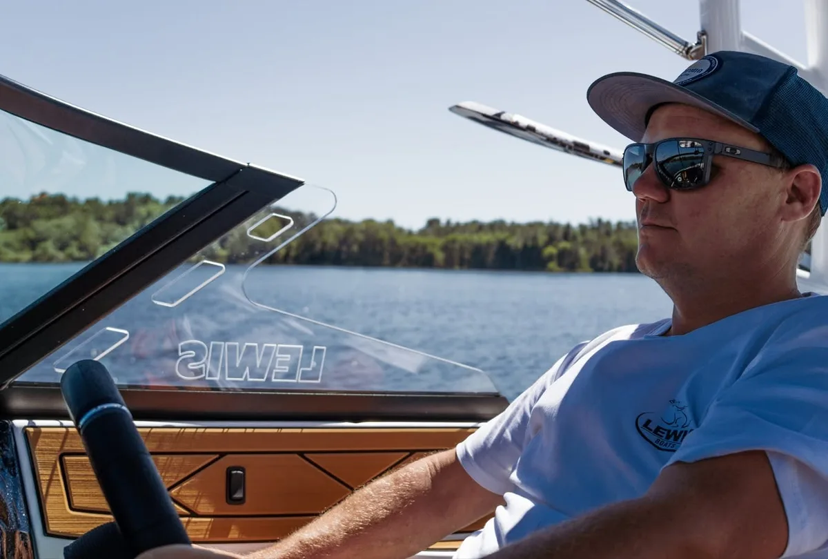 A man at the wheel of a Lewis boat out on the water