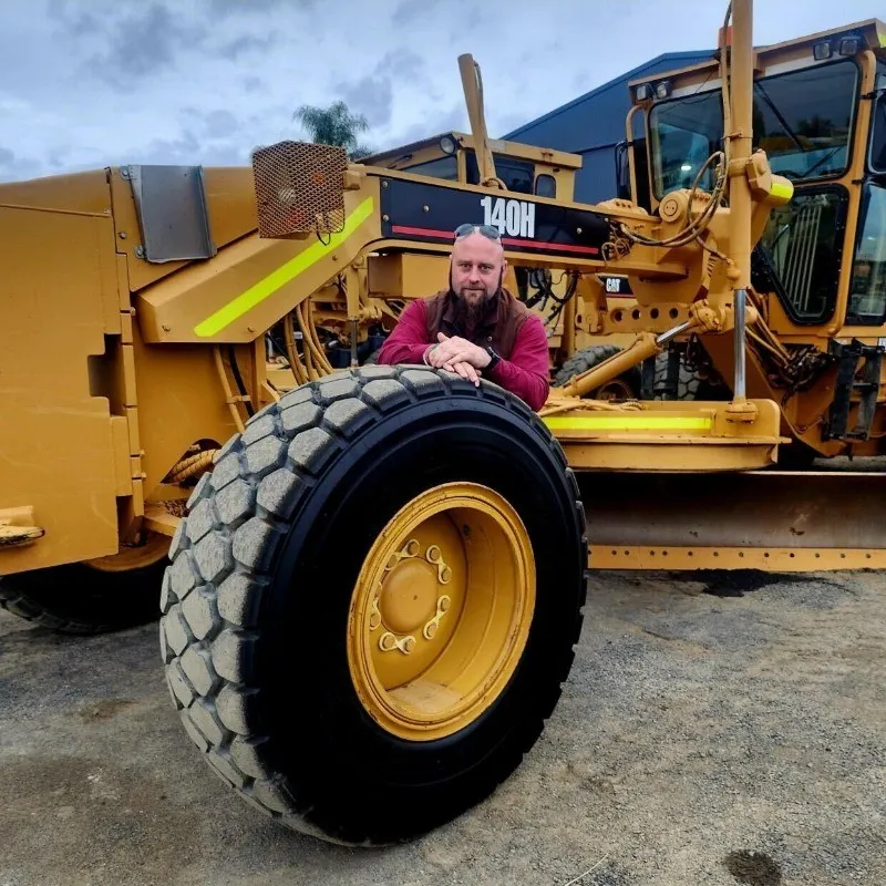 Miguel Grima leaning on the wheel of a grader