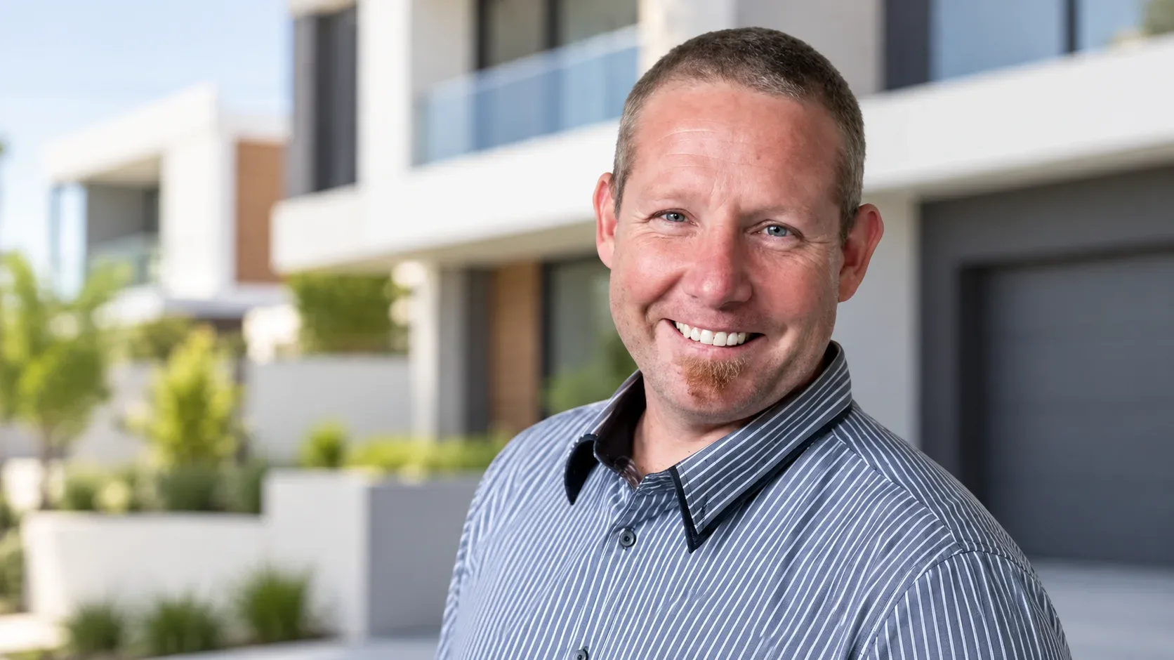 Nigel Archer smiling outside a modern residential building