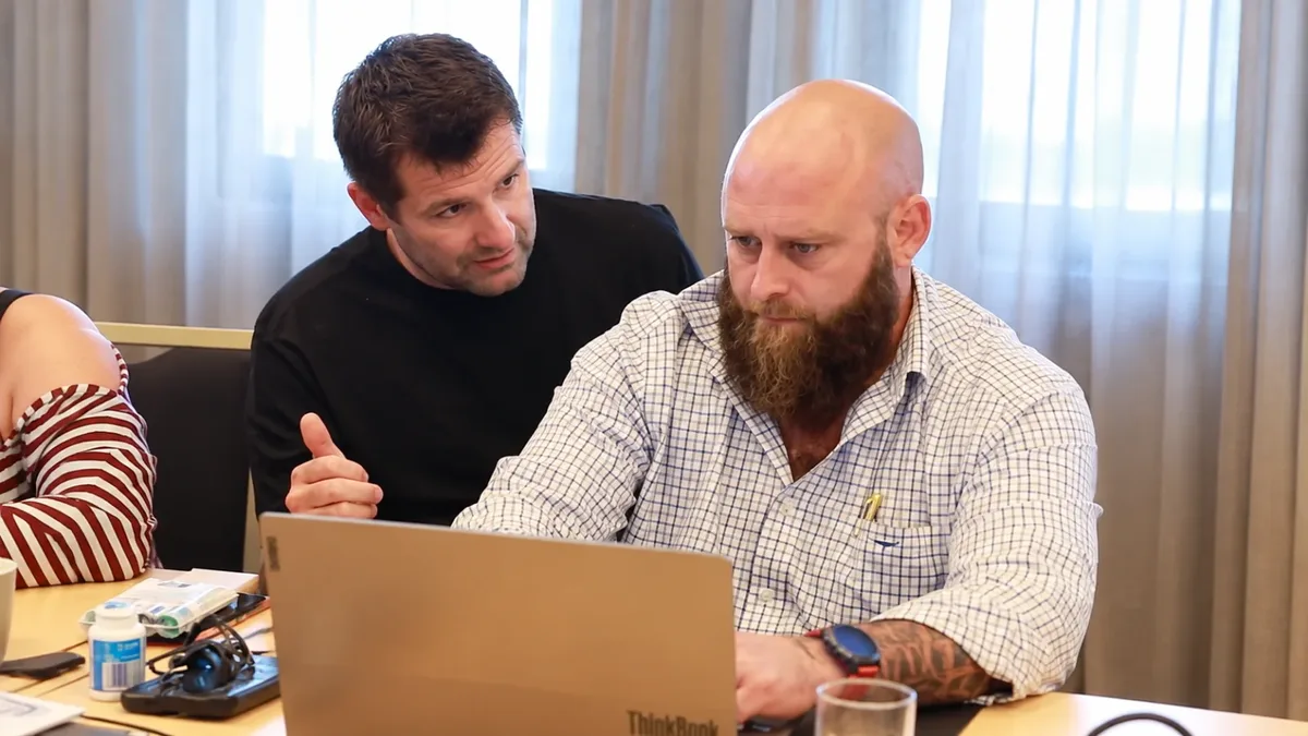 Two men working through something together on a laptop