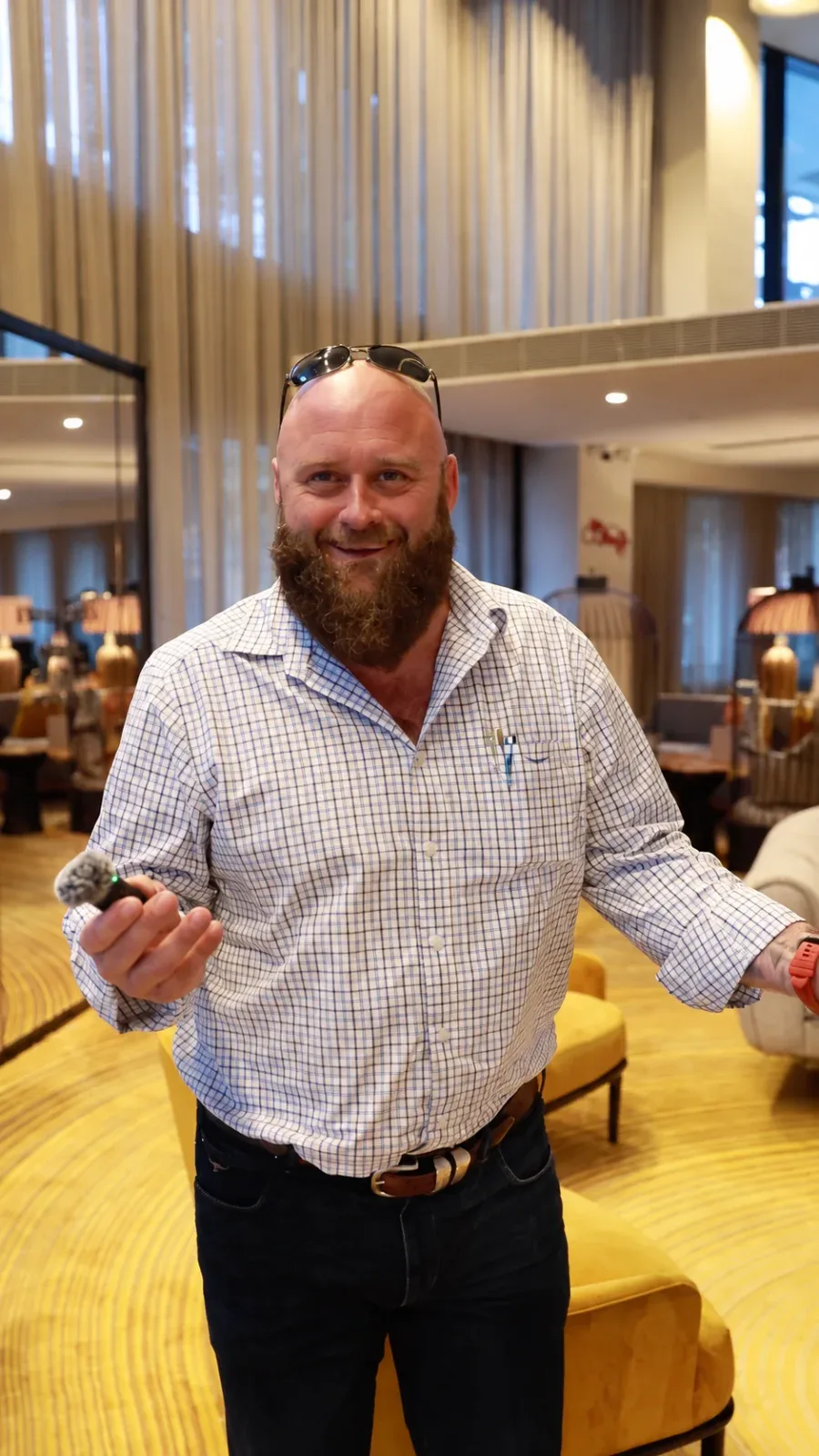 A smiling man in a checked shirt standing in a function room