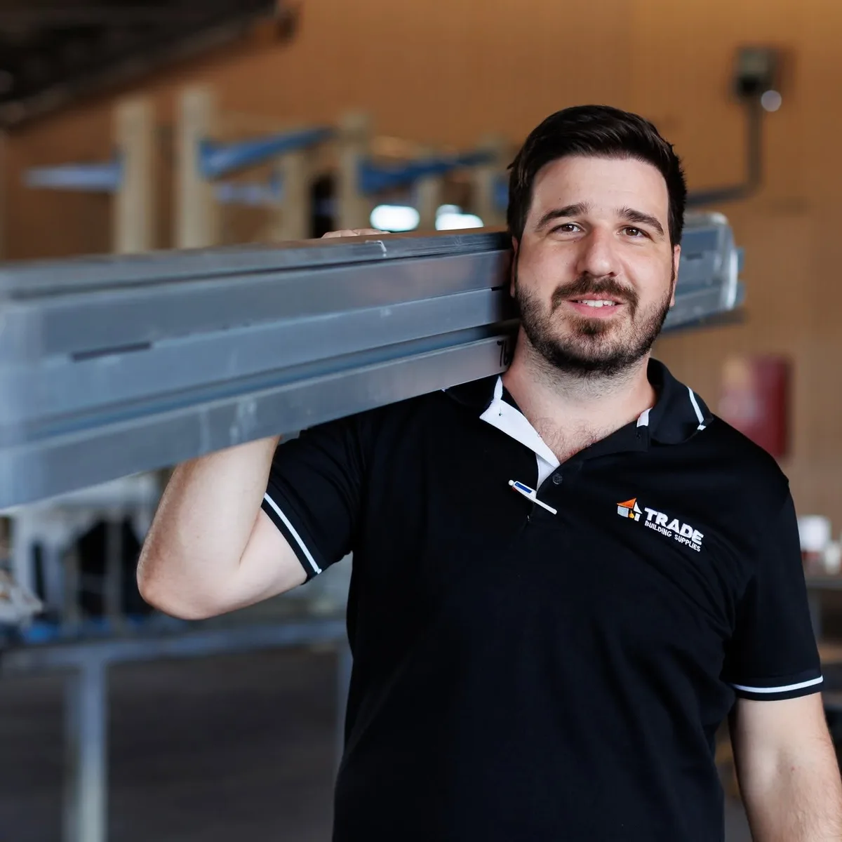 A Trade Building Supplies team member carrying steel lengths on his shoulder