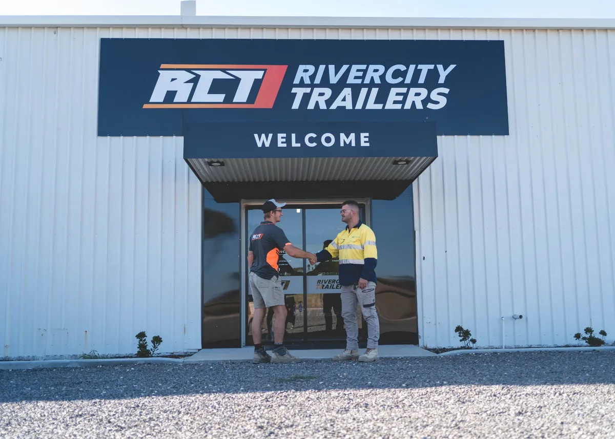 Two men at the Rivercity Trailers welcome sign