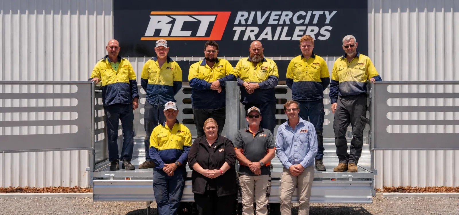 The Rivercity Trailers team standing with trailers in front of the company sign